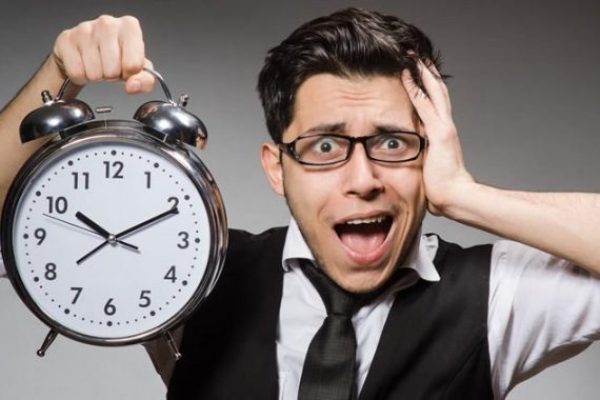 Hombre preocupado tocando su cabeza y sosteniendo un reloj en mano